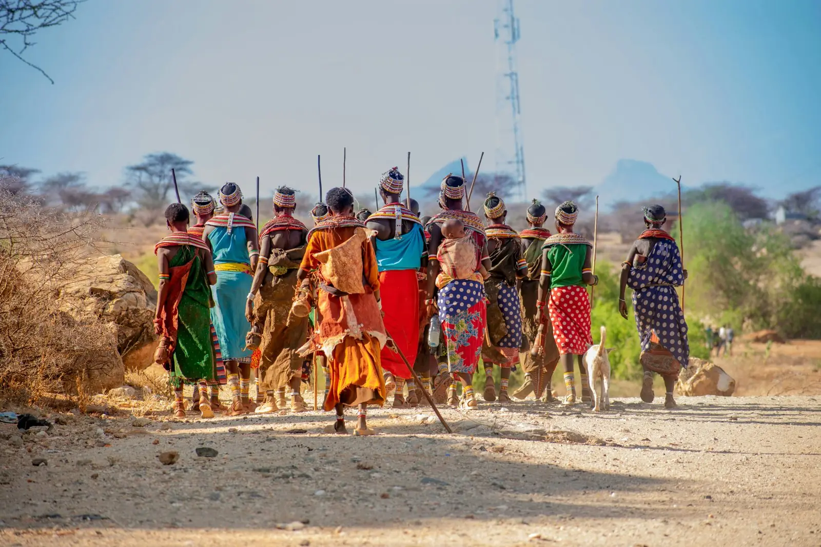 Samburu women in beaded collars walking along a dusty road